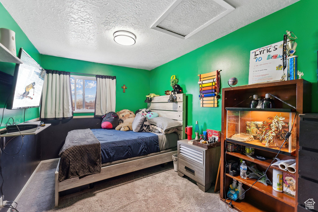 Carpeted bedroom with a textured ceiling and attic access