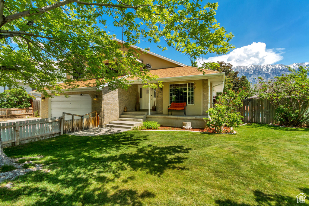 View of front of property featuring an attached garage, a mountain view, a porch, brick siding, and roof with shingles
