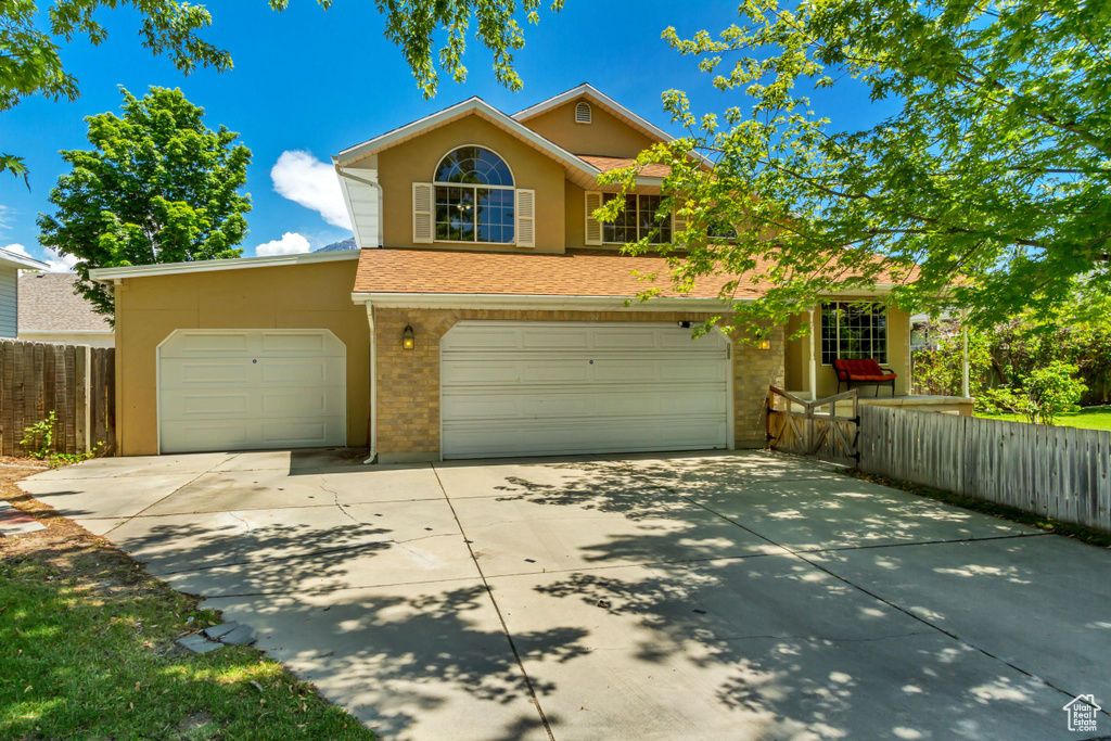 Traditional home with concrete driveway, brick siding, an attached garage, and stucco siding