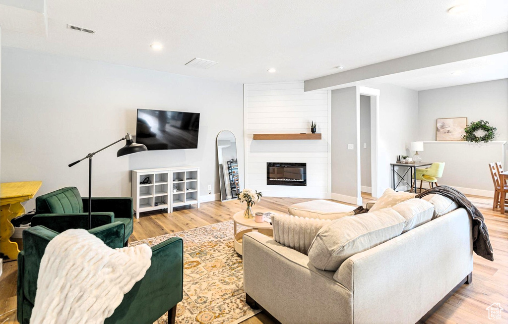 Living area with visible vents, a large fireplace, baseboards, and wood finished floors