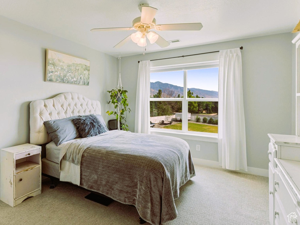 Bedroom featuring a ceiling fan, baseboards, a mountain view, and light carpet