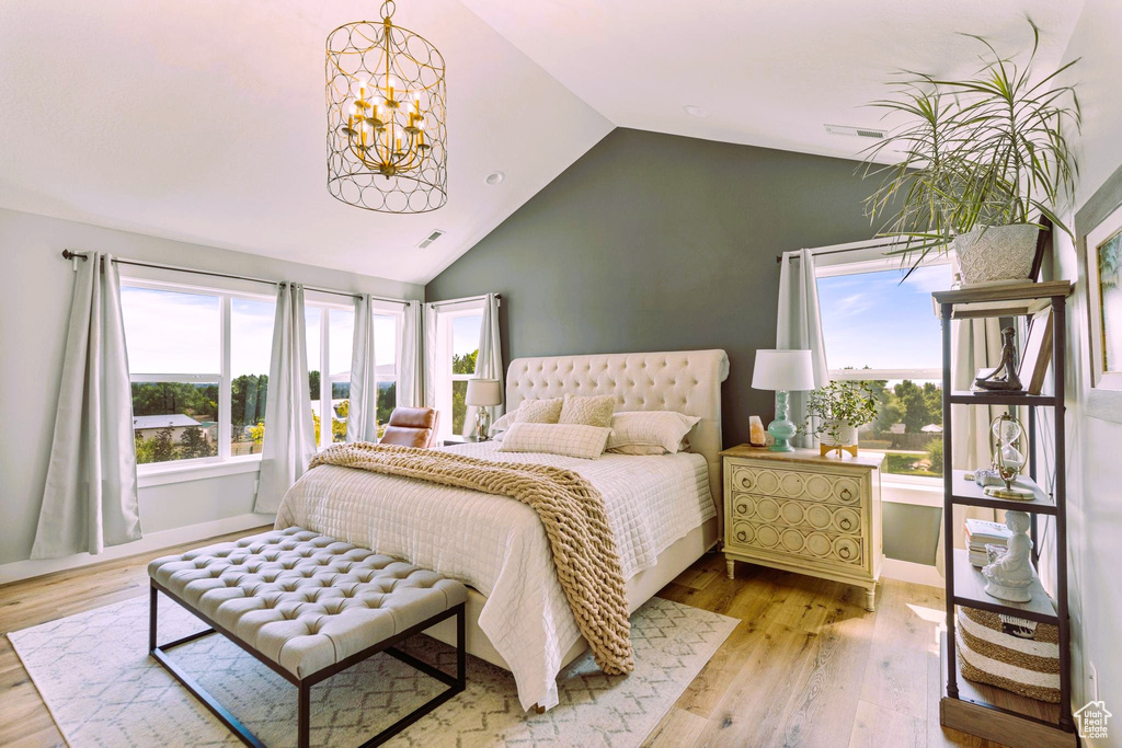 Bedroom with vaulted ceiling, multiple windows, and wood finished floors