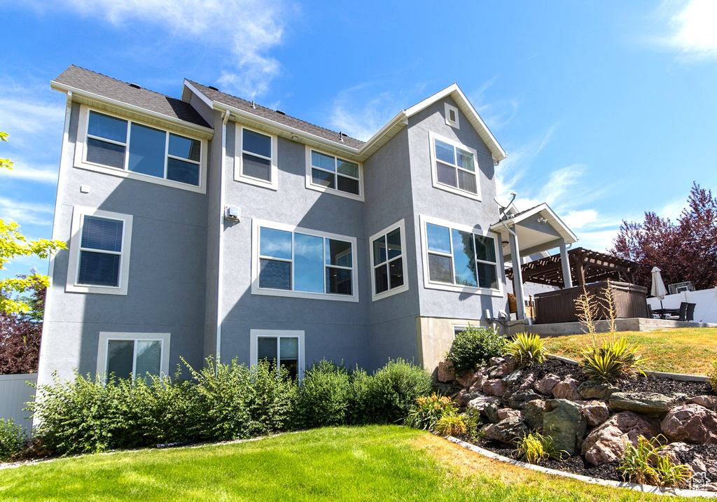 Rear view of property with stucco siding, a yard, and fence