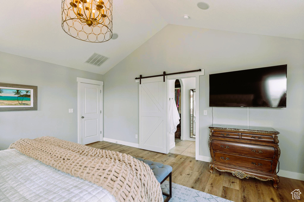 Bedroom featuring visible vents, wood finished floors, a barn door, baseboards, and a chandelier