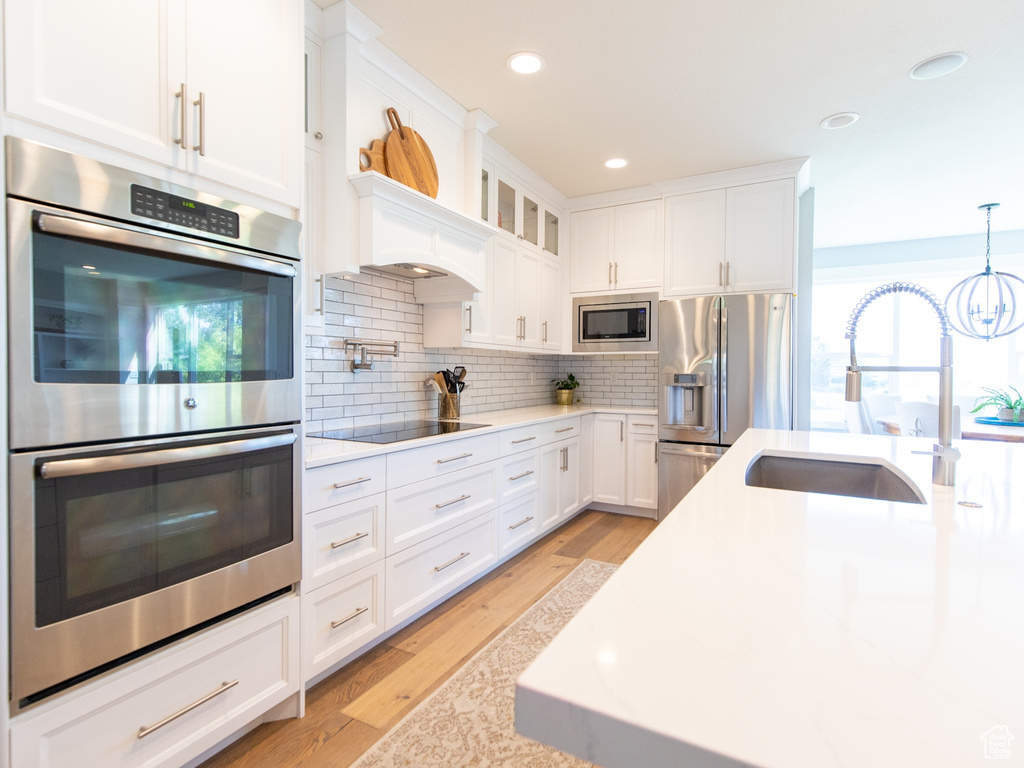 Kitchen with tasteful backsplash, appliances with stainless steel finishes, white cabinetry, and a sink