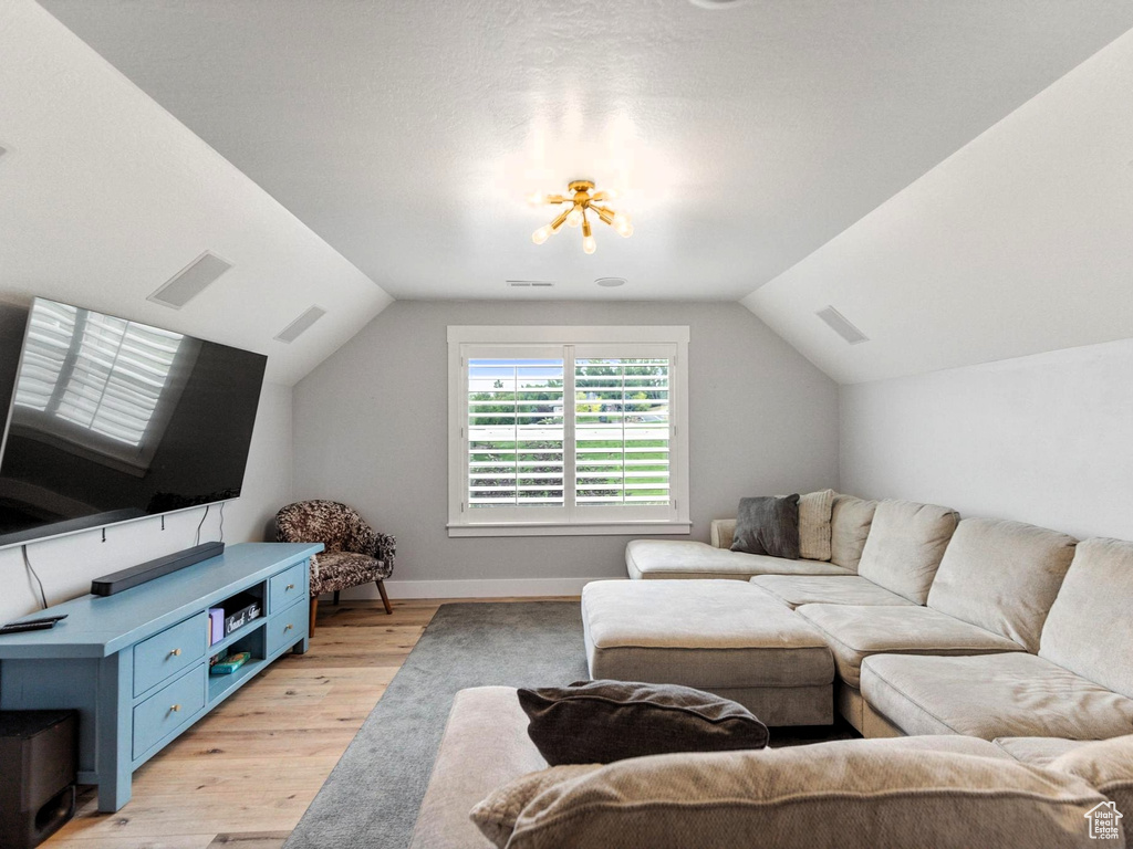 Living area featuring light wood finished floors, visible vents, baseboards, and lofted ceiling