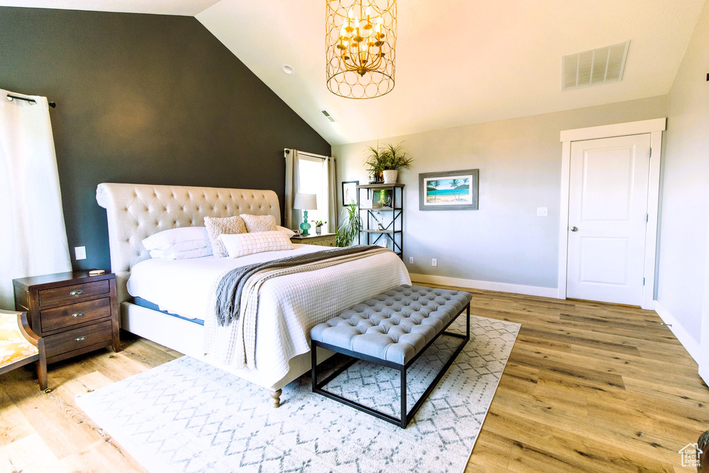 Bedroom featuring lofted ceiling, wood finished floors, visible vents, and baseboards