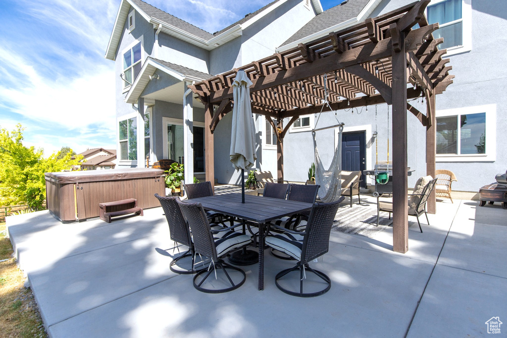 View of patio / terrace featuring a hot tub, outdoor dining area, and a pergola