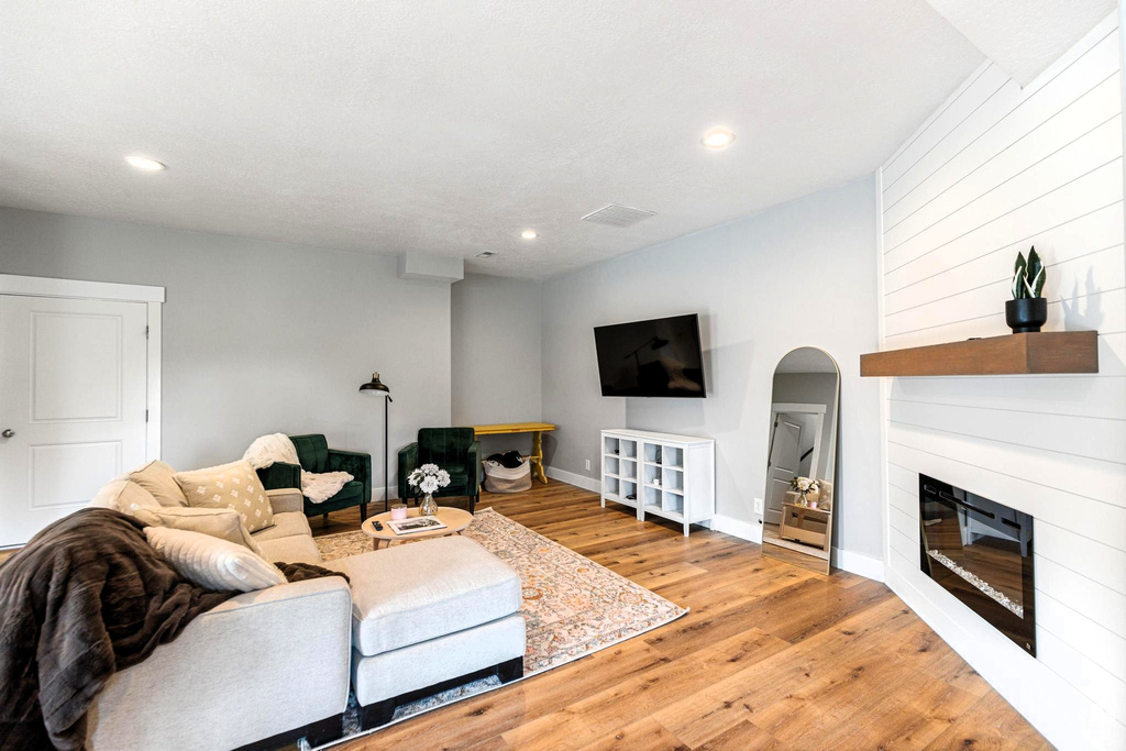 Living area with baseboards, recessed lighting, a fireplace, wood finished floors, and arched walkways