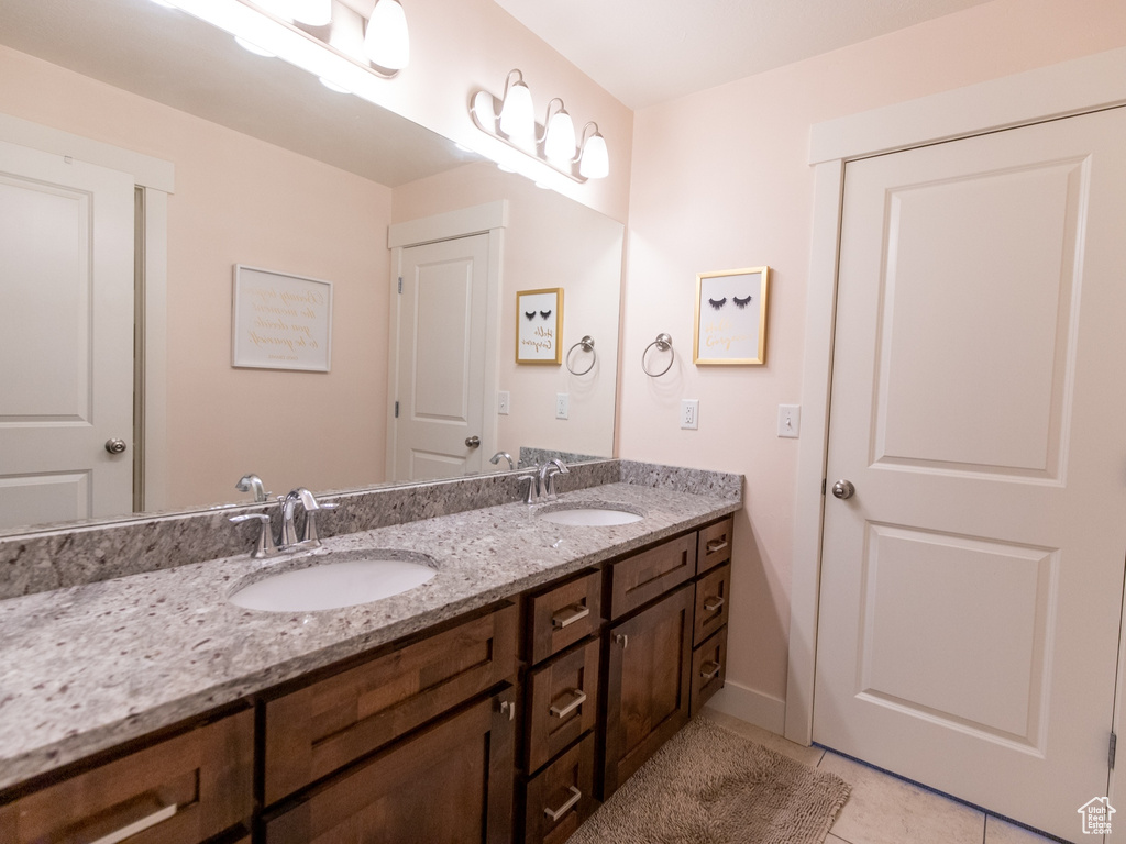Bathroom with tile patterned flooring, double vanity, baseboards, and a sink
