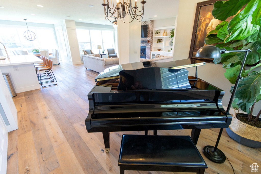Interior space with an inviting chandelier, a brick fireplace, recessed lighting, and light wood-style floors