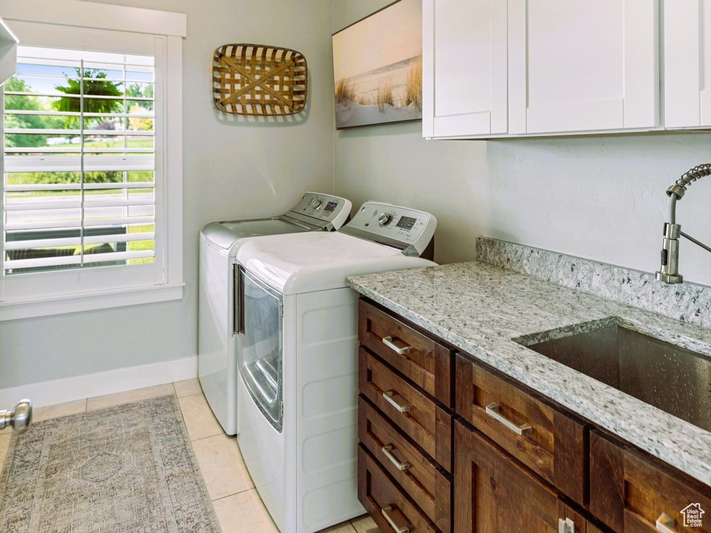 Washroom featuring light tile patterned flooring, cabinet space, a sink, a textured ceiling, and independent washer and dryer