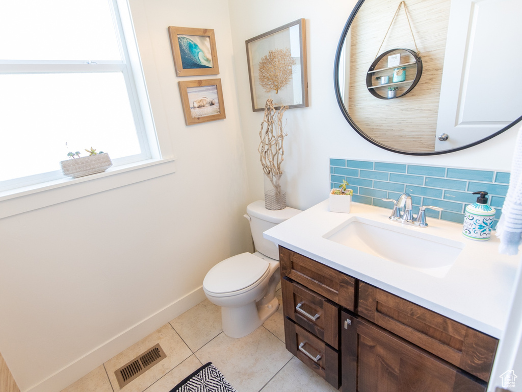 Bathroom featuring tile patterned floors, visible vents, toilet, backsplash, and vanity