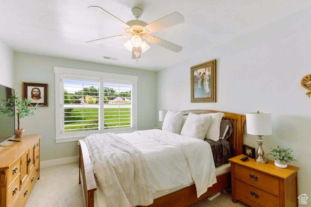 Bedroom featuring visible vents, baseboards, light colored carpet, and ceiling fan