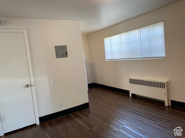 Unfurnished room featuring radiator heating unit, wood finished floors, and baseboards