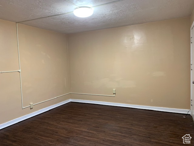 Spare room featuring dark wood finished floors, baseboards, and a textured ceiling
