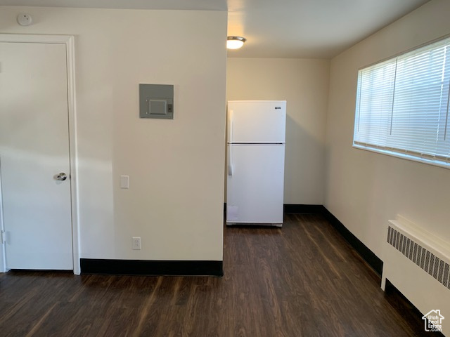 Kitchen featuring radiator, baseboards, electric panel, freestanding refrigerator, and dark wood-type flooring