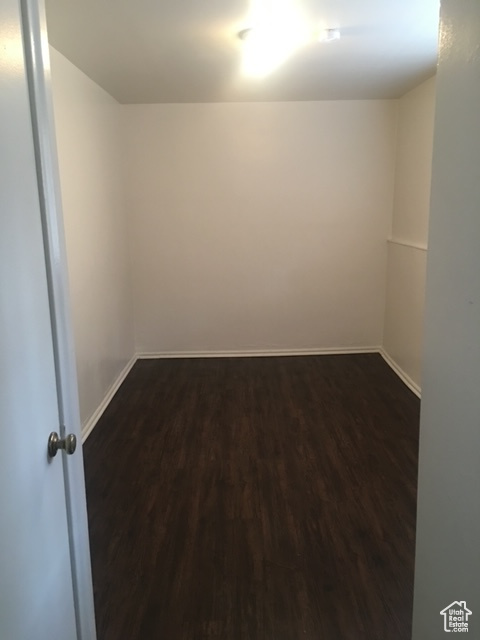 Empty room featuring dark wood-type flooring and baseboards