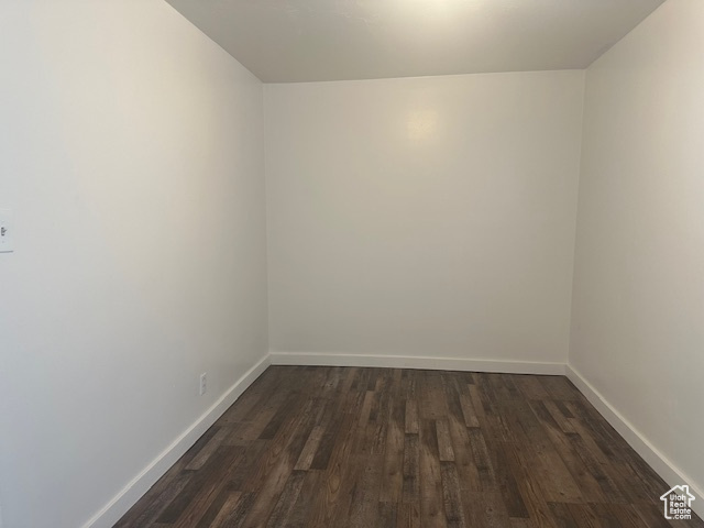Spare room featuring baseboards and dark wood-style floors