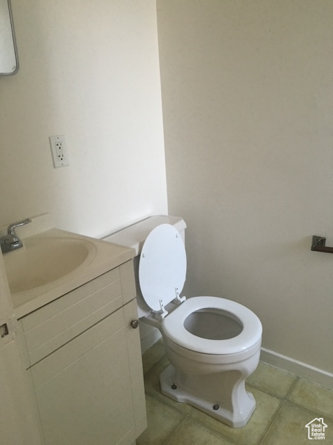 Bathroom featuring baseboards, toilet, vanity, and tile patterned flooring