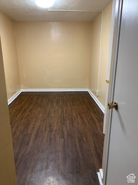 Spare room featuring baseboards, dark wood-style flooring, and a textured ceiling