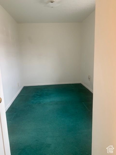 Empty room featuring baseboards and dark colored carpet
