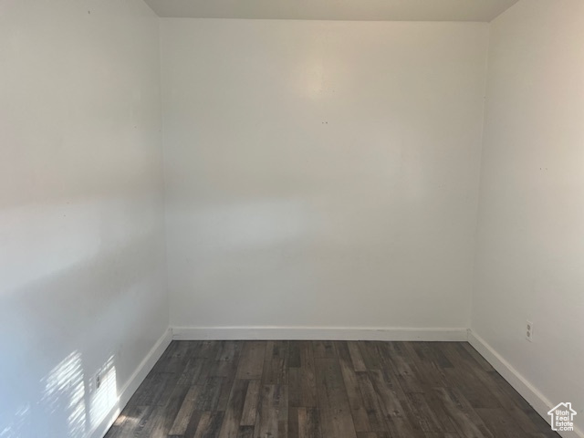 Empty room featuring dark wood-type flooring and baseboards