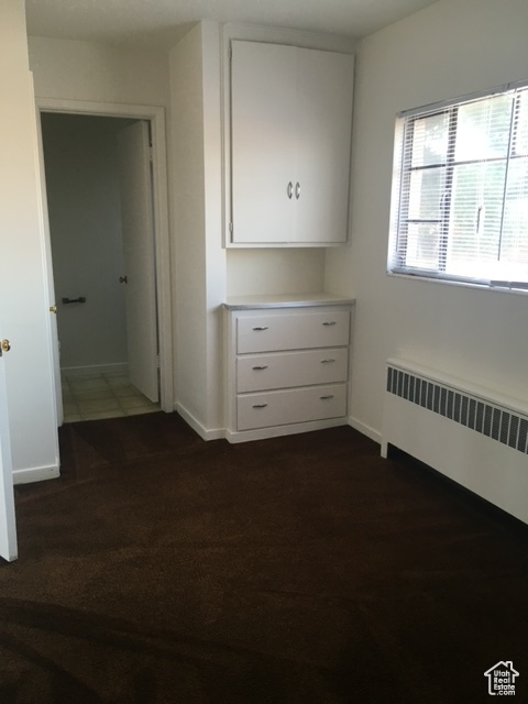 Unfurnished bedroom with radiator heating unit and baseboards