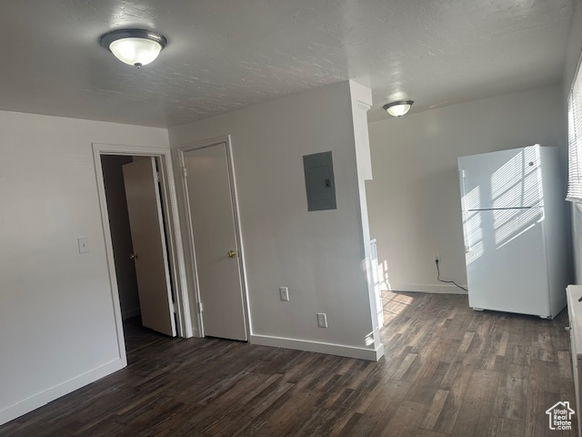Spare room with electric panel, baseboards, a textured ceiling, and dark wood-style flooring