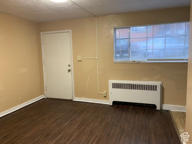 Unfurnished room with radiator heating unit, baseboards, and wood finished floors