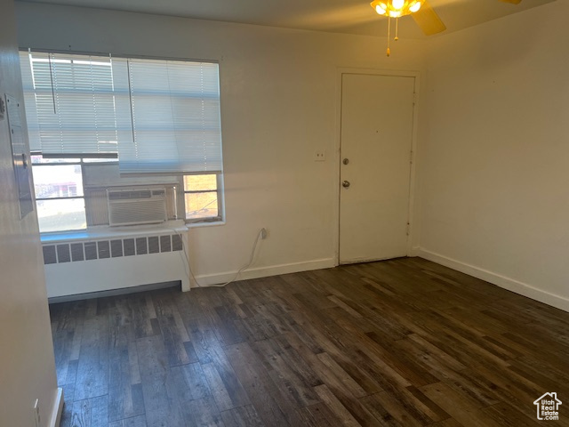 Spare room featuring cooling unit, baseboards, dark wood-style floors, and radiator heating unit