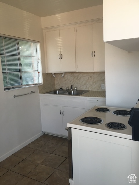 Kitchen with white cabinetry, a sink, backsplash, and white electric stove