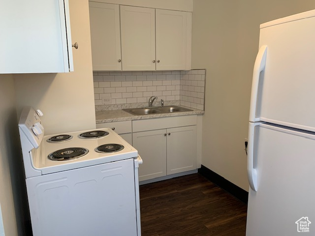 Kitchen with dark wood finished floors, light countertops, white appliances, white cabinetry, and a sink
