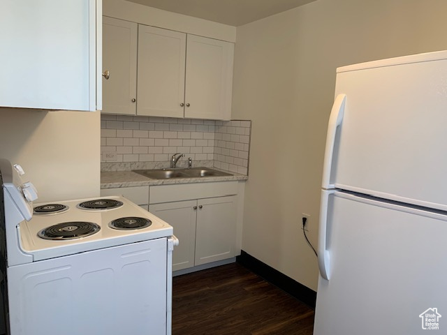 Kitchen featuring a sink, tasteful backsplash, white appliances, light countertops, and dark wood-style flooring