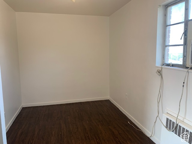 Empty room featuring baseboards and dark wood finished floors