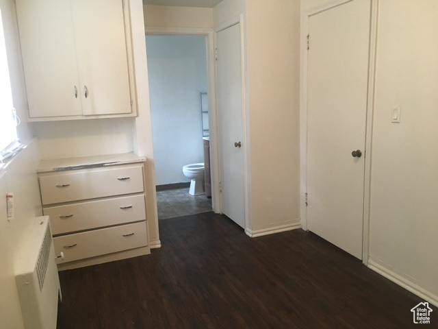Hallway featuring radiator, baseboards, and dark wood-style flooring