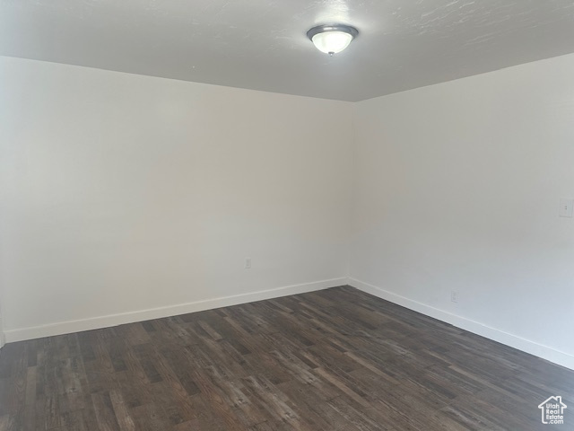 Empty room featuring dark wood finished floors and baseboards