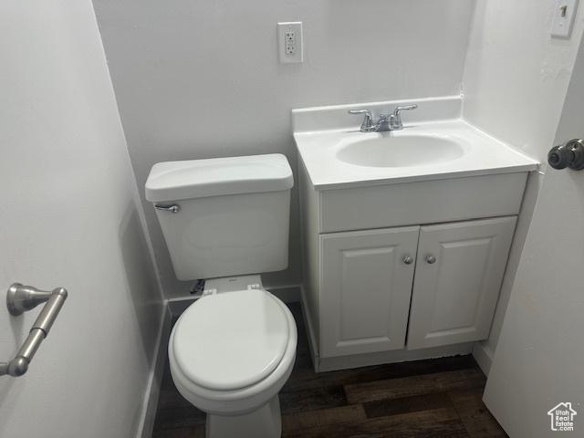 Half bathroom featuring toilet, vanity, and wood finished floors