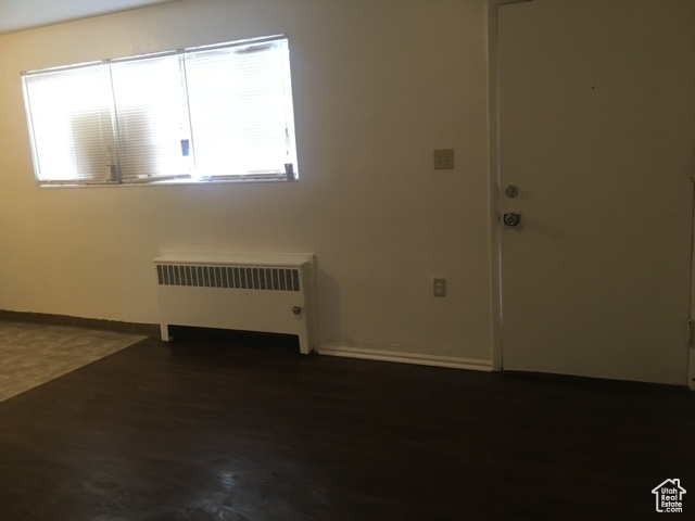 Spare room with baseboards, radiator, and wood finished floors