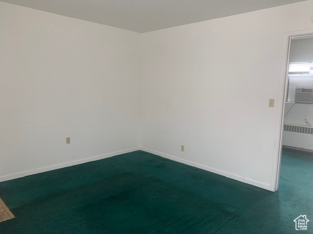 Unfurnished room with dark colored carpet, baseboards, and radiator heating unit
