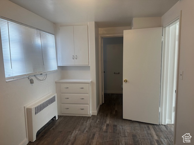 Interior space featuring light countertops, white cabinets, radiator, and dark wood-style floors