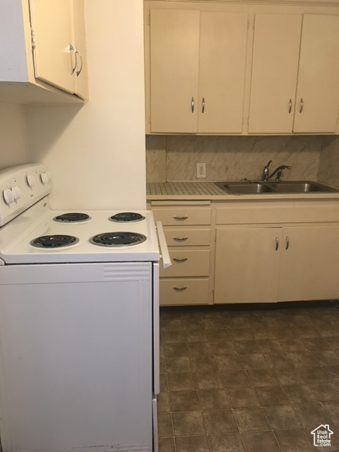 Kitchen with white range with electric cooktop, a sink, white cabinetry, light countertops, and decorative backsplash