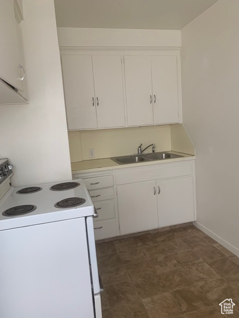 Kitchen featuring white cabinetry, light countertops, white electric range, and a sink