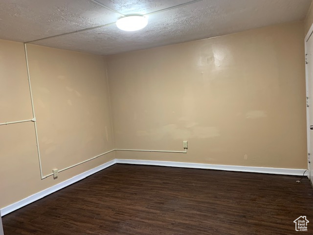 Spare room with dark wood finished floors, a textured ceiling, and baseboards