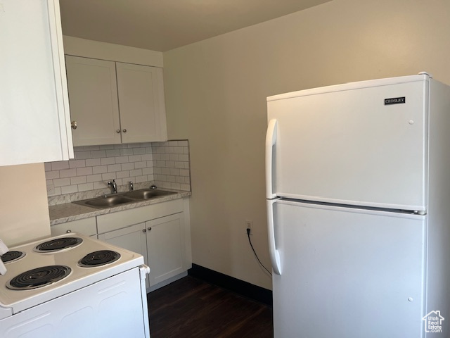 Kitchen with white appliances, dark wood-style flooring, a sink, decorative backsplash, and light countertops