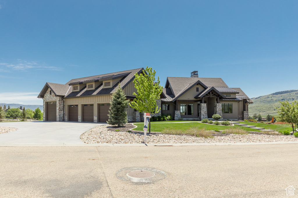 View of front of home with stone siding, driveway, a mountain view, and a chimney