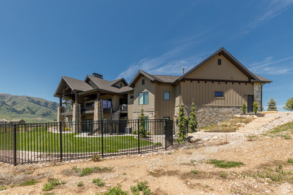 View of side of home featuring stone siding, a garage, a balcony, board and batten siding, and a mountain view