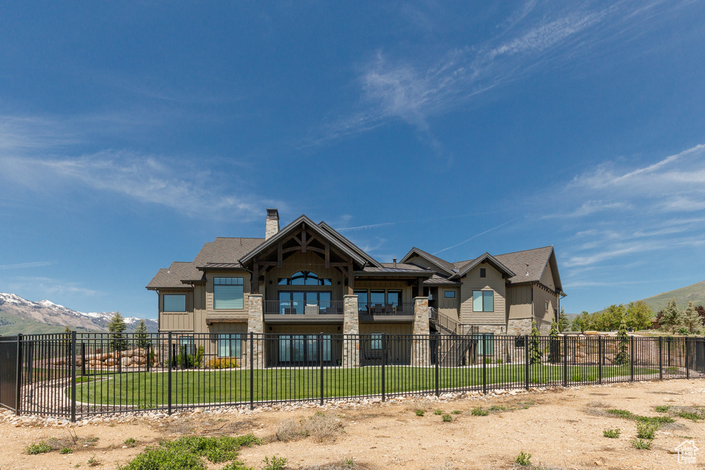 Back of property with stone siding, a chimney, a mountain view, and board and batten siding