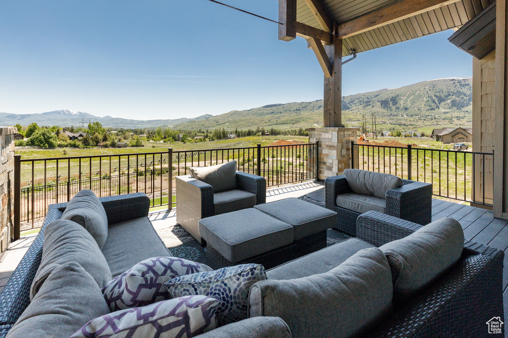 Wooden deck with an outdoor living space, a mountain view, and a view of countryside