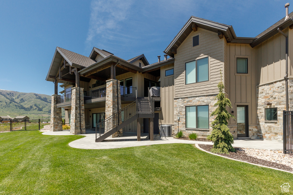 Rear view of house featuring a patio area, cooling unit, stone siding, board and batten siding, and stairway